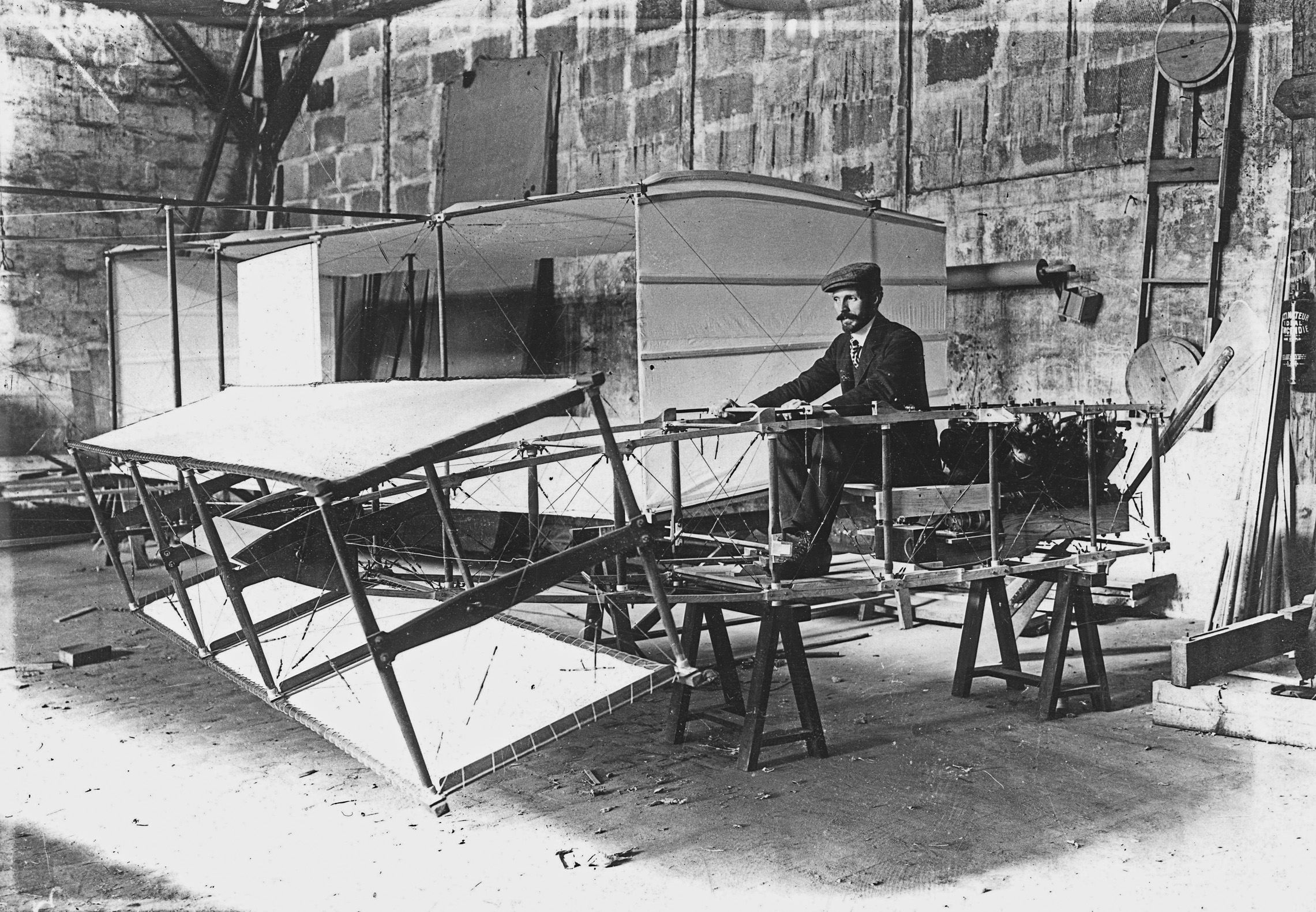 Henry Farman, dans l'atelier de la rue de la ferme essaye les commandes de son avion. Archives municipales de Boulogne-Billancourt